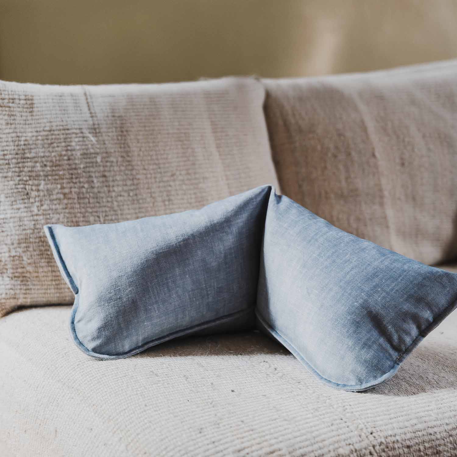 Coussin cervical bleu clair posé sur un canapé