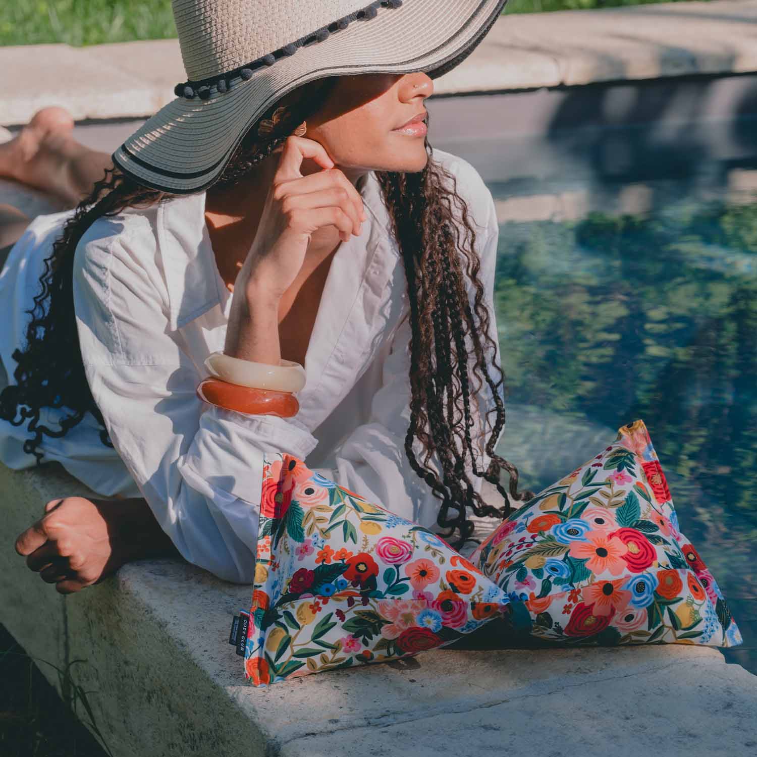 Jeune femme en bord de piscine avec coussin cervical motif fleurs