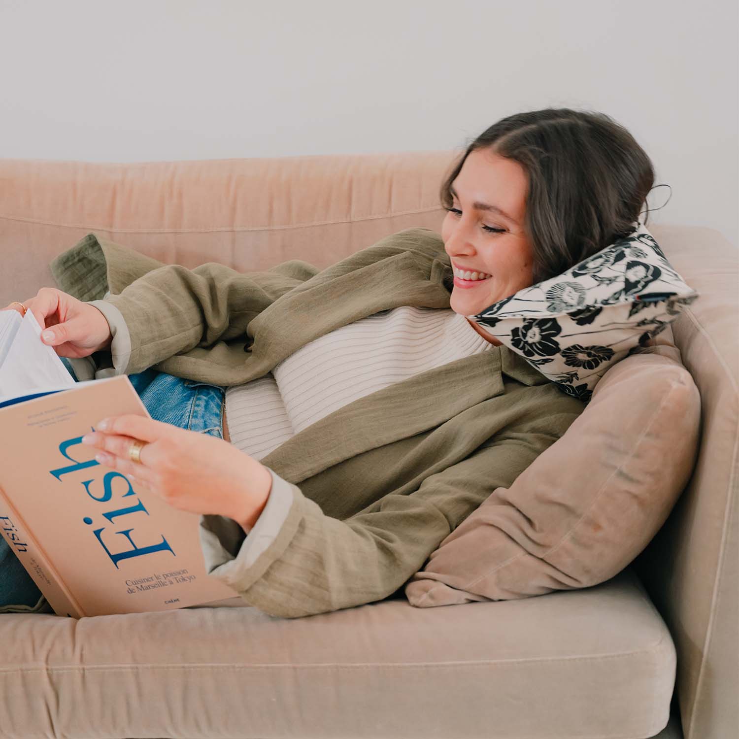Femme lisant sur un canapé avec coussin cervical motif fleurs noir et blanc