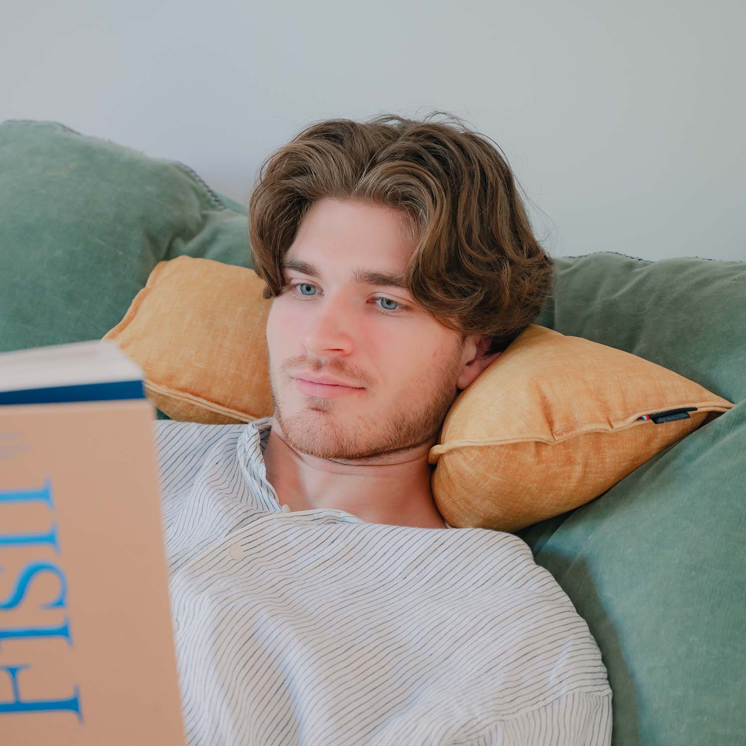 Homme lisant au lit avec coussin cervical velours jaune