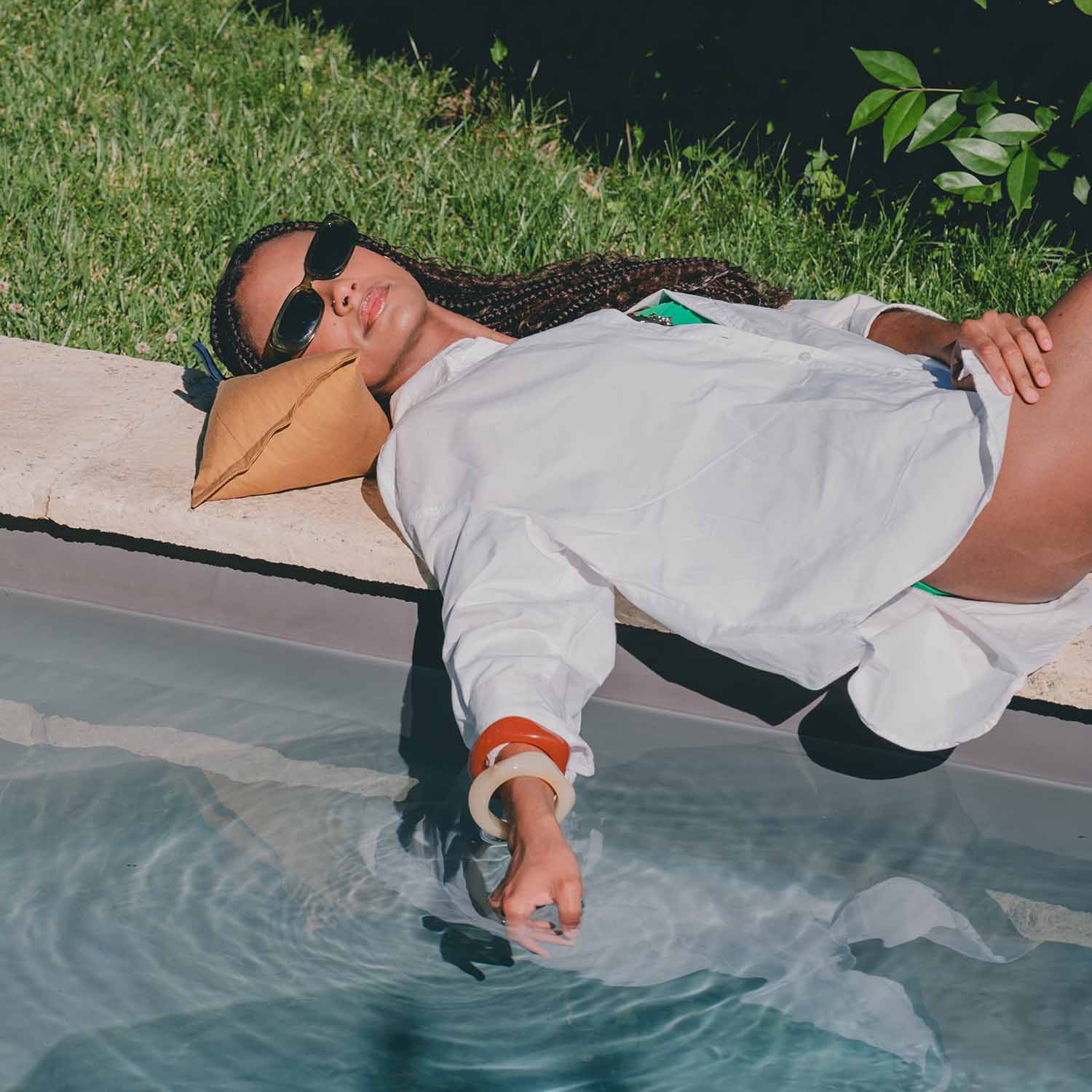 Femme allongée en bord de piscine avec coussin cervical coloris moutarde