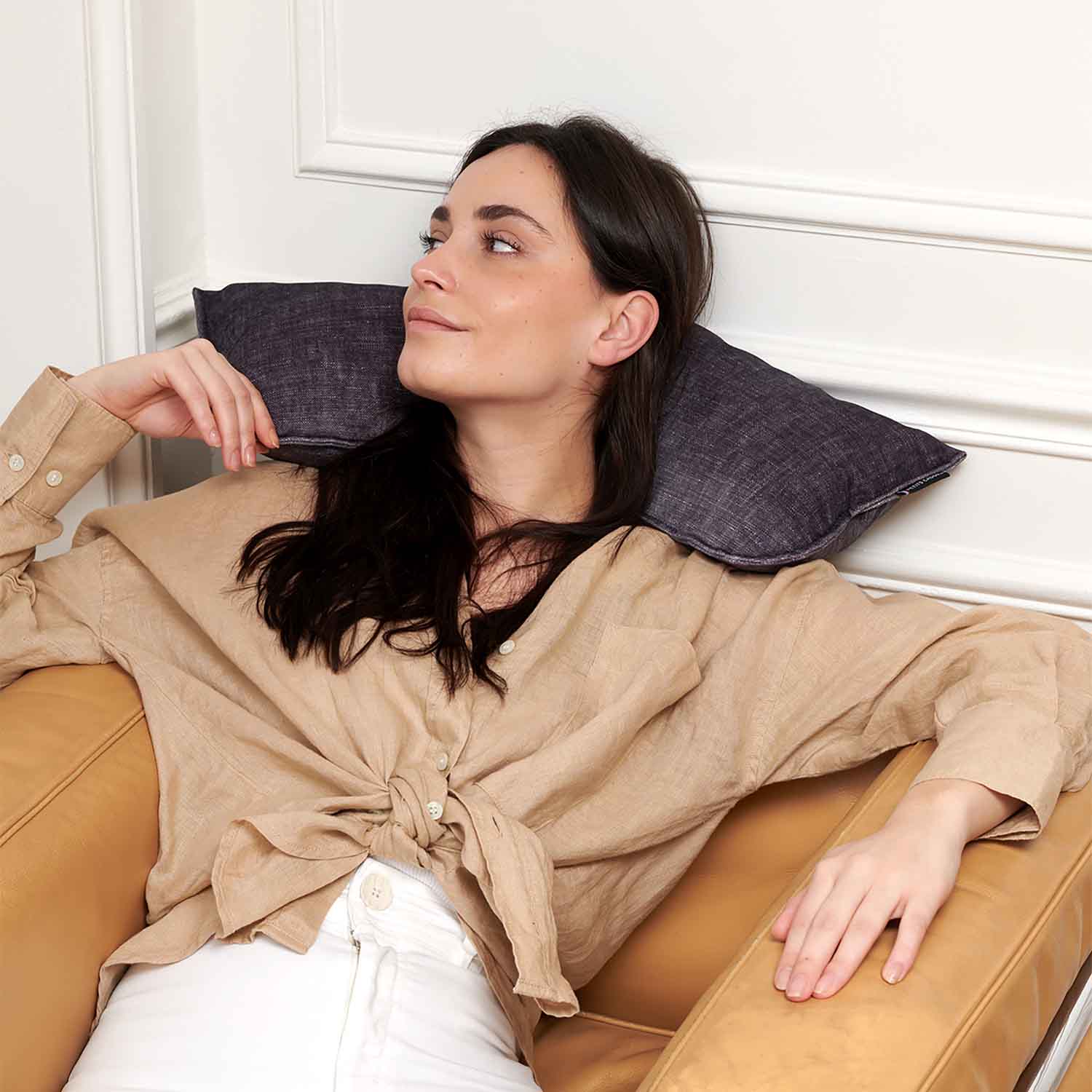 Femme assise sur canapé avec coussin cervical gris anthracite en velours