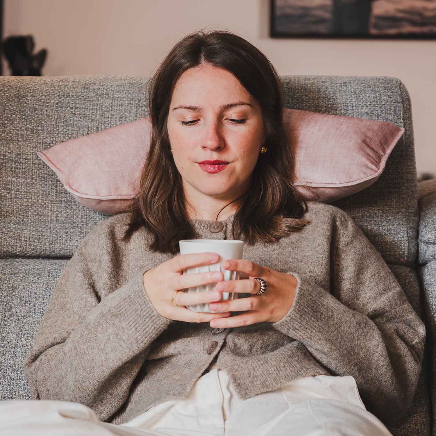 Femme assise sur canapé avec coussin cervical velours rose