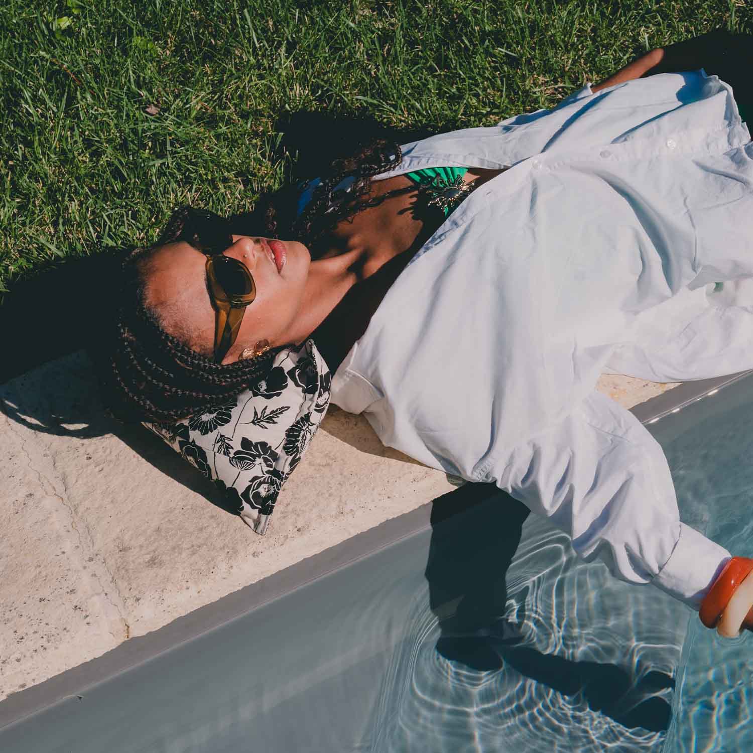 Femme allongée en bord de piscine avec coussin cervical motif fleur