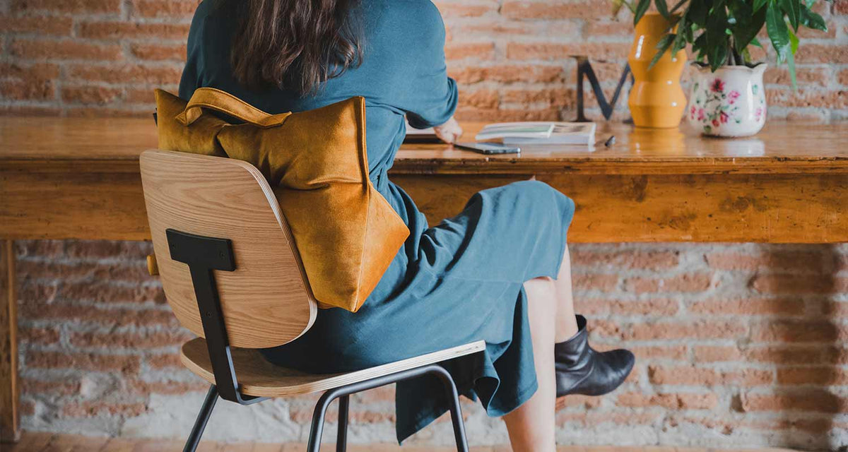 femme en télétravail, de dos, avec coussin lombaire coloris jaune or