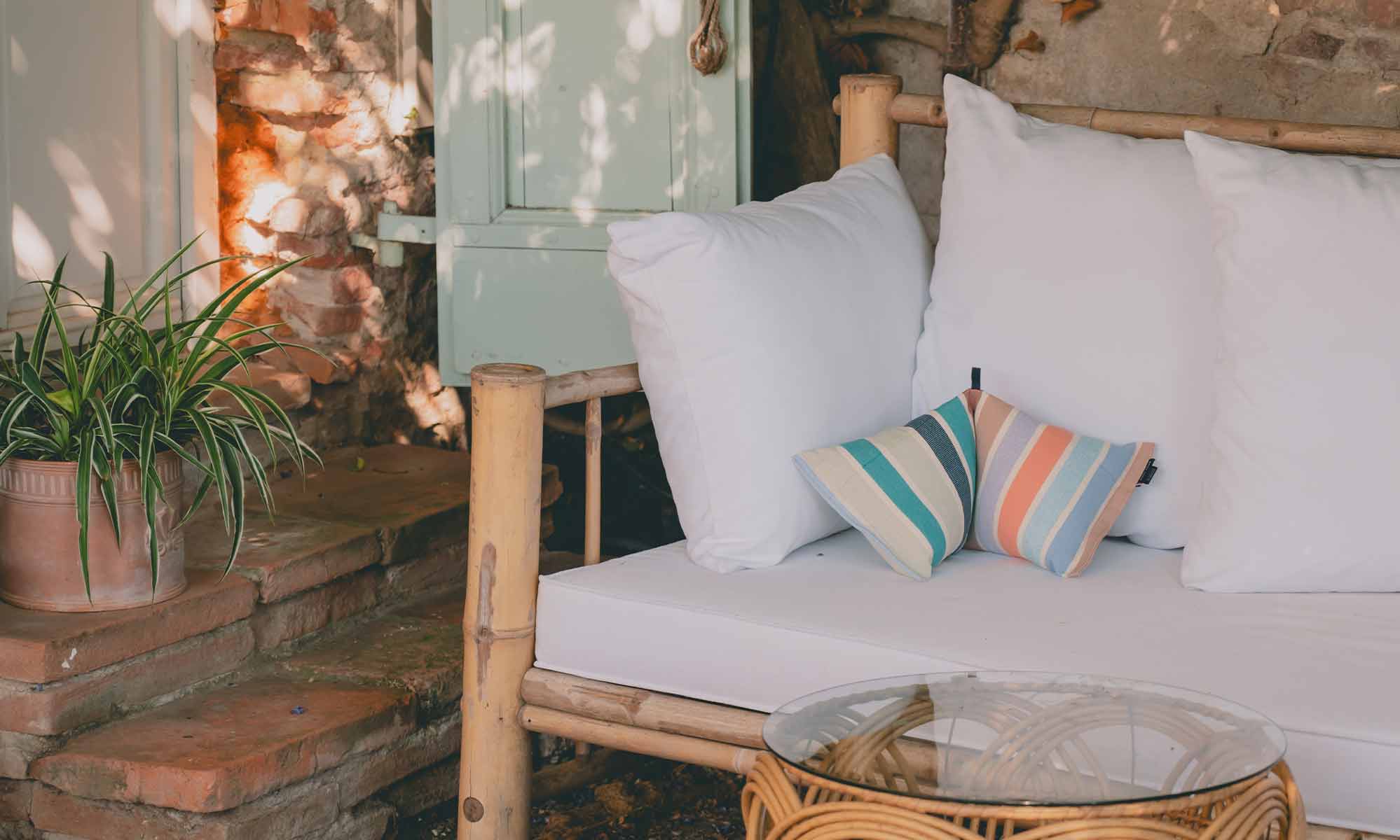 Coussin cervical à rayure posé sur banquette extérieure en bambou