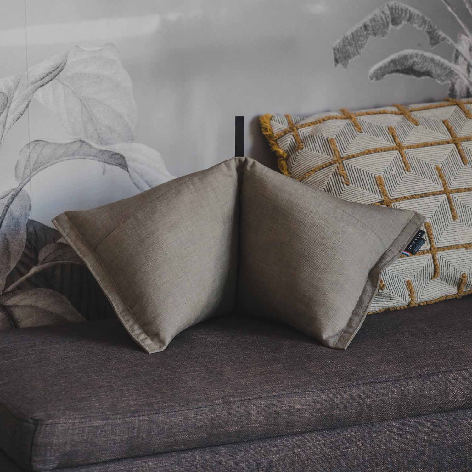 Coussin cervical coloris taupe posé sur banquette grise