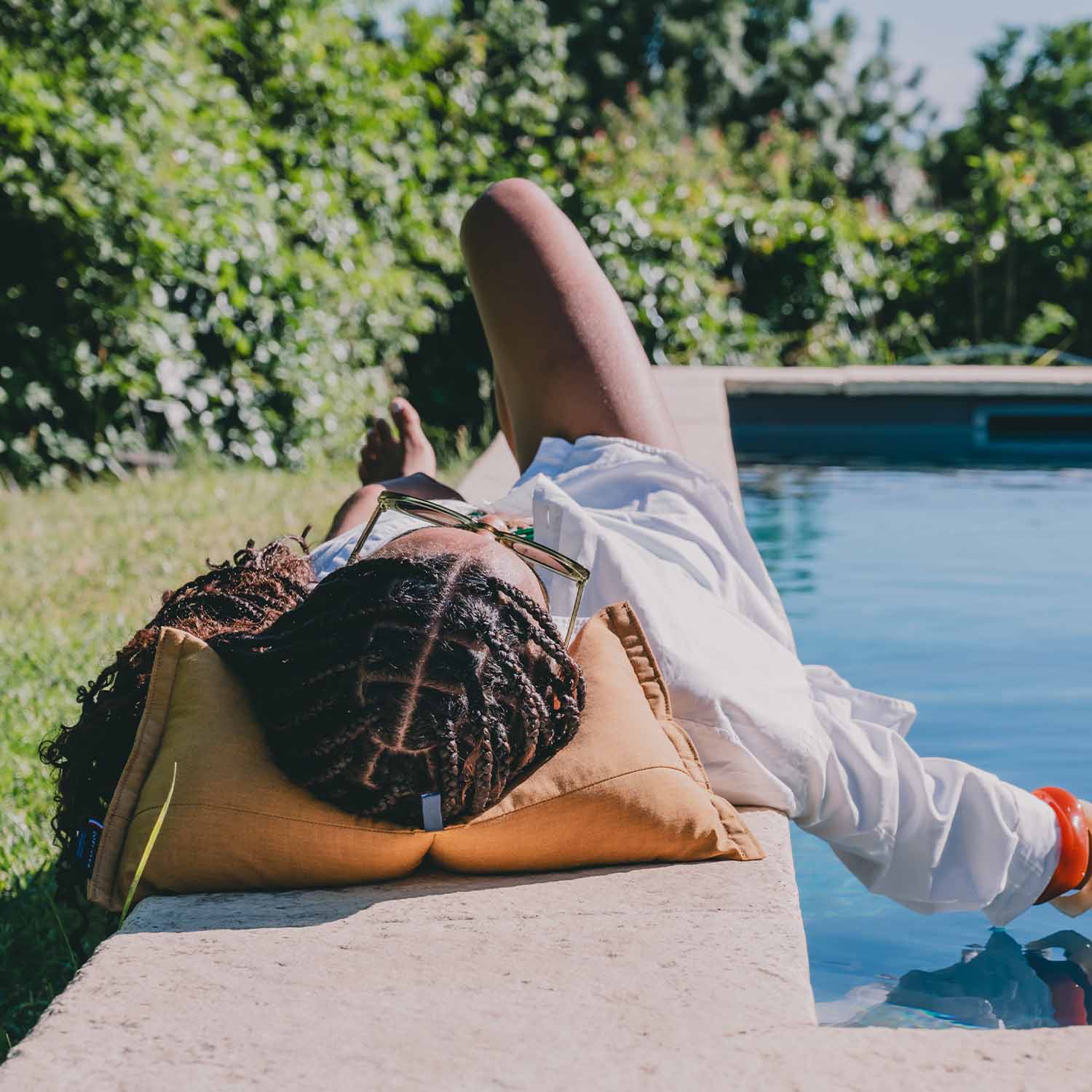 Femme allongée en bord de piscine avec coussin cervical coloris jaune